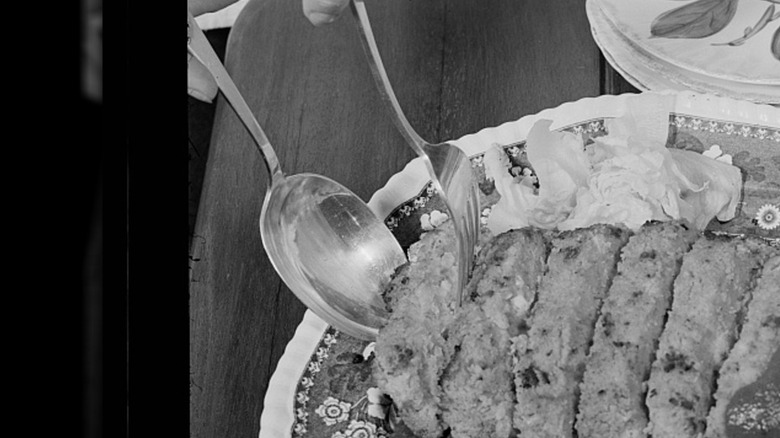 Black and white photo of a baked bean loaf with sauce on a floral plate.