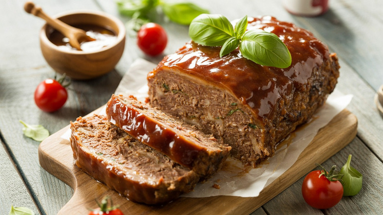 Meatloaf on a table with tomatoes and basil