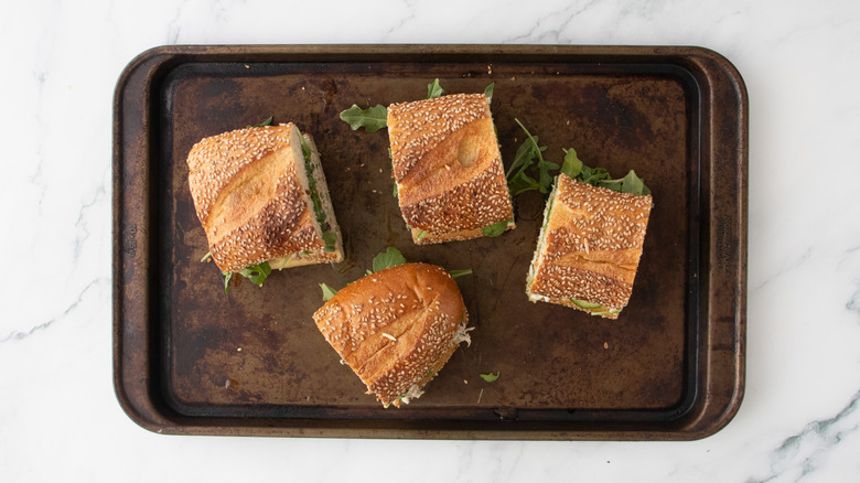 Four portions of tuna salad sandwiches on a baking sheet.