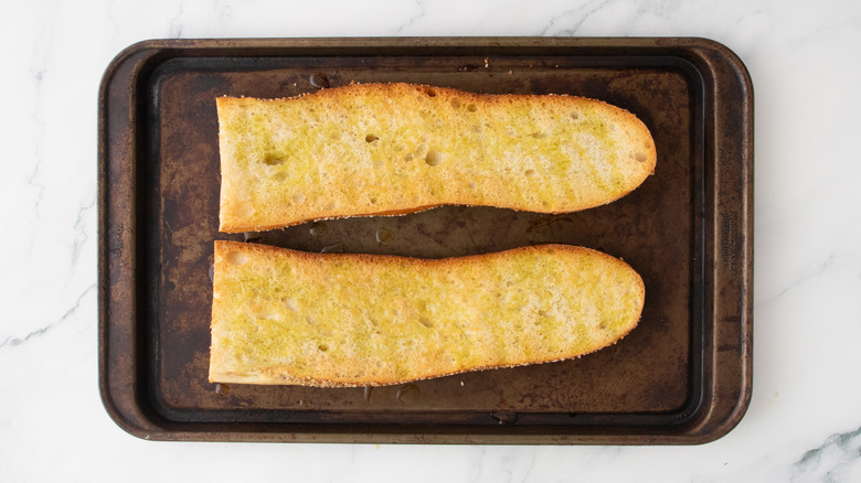 Half of a large baguette toasted on a baking sheet