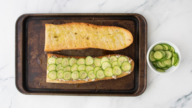Tuna salad on a large toasted baguette topped with cucumber