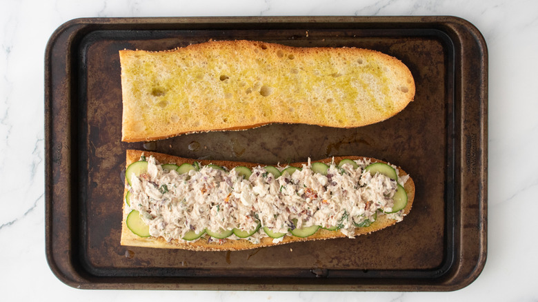 A layered tuna salad on a large toasted baguette