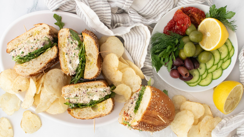 Overhead shot of Mediterranean tuna salad sandwiches with salad ingredients on the side.