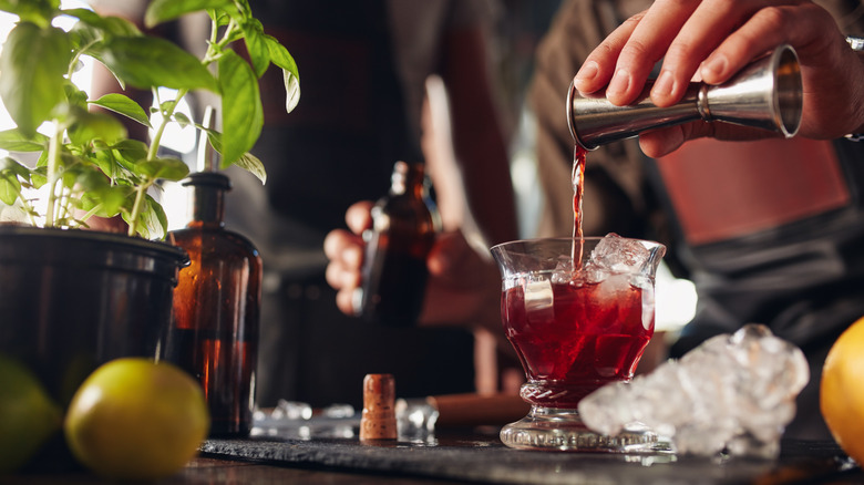 A bartender mixing a cocktail and pouring it into a glass with ice