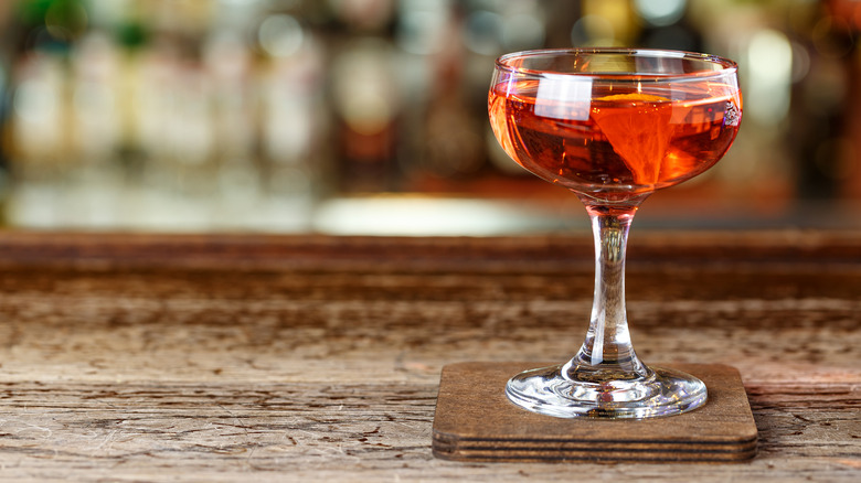 An El Presidente cocktail in a coupe glass on wood coaster set on wood table