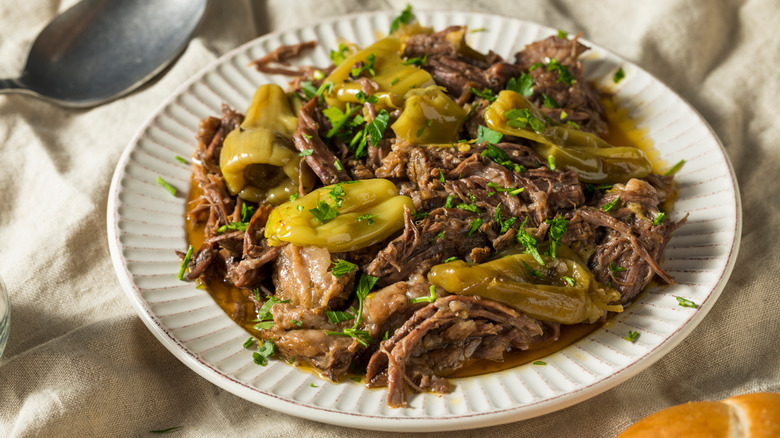 A plate of Mississippi pot roast meat, with pepperoncini peppers on top.