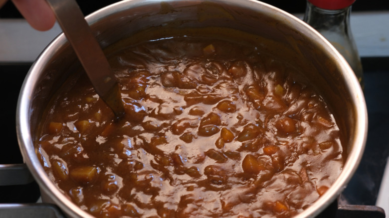 A pot of rich, thick curry being cooked.
