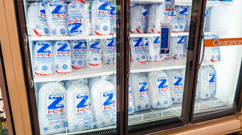 Bags of ice stocked up in commercial freezer in store.