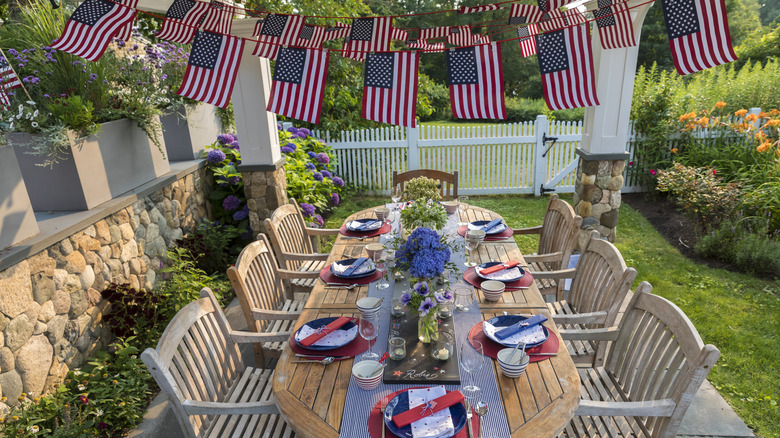 A table in the backyard decorated with flags and blue and white plates