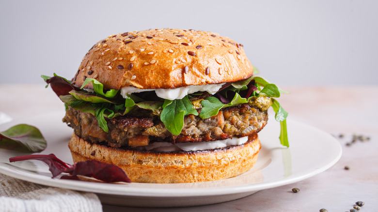 Vegan burger with lentil cutlet on bun with veggies.