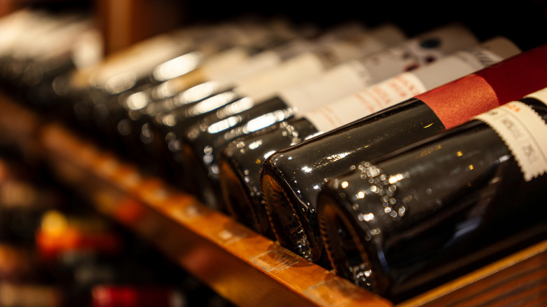 Red wine bottles on a wooden shelf