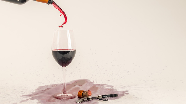 Messily pouring Mendoza malbec in a glass next to corkscrew and stopper