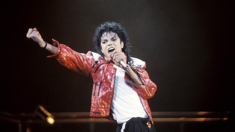 Michael Jackson holding a microphone and singing onstage.