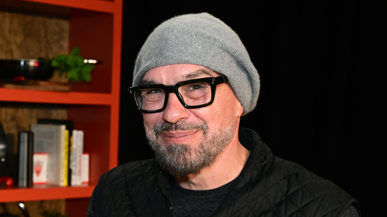Michael Symon smiling in a gray beanie and black framed glasses