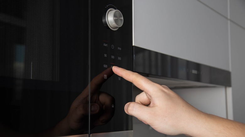finger pressing button on microwave