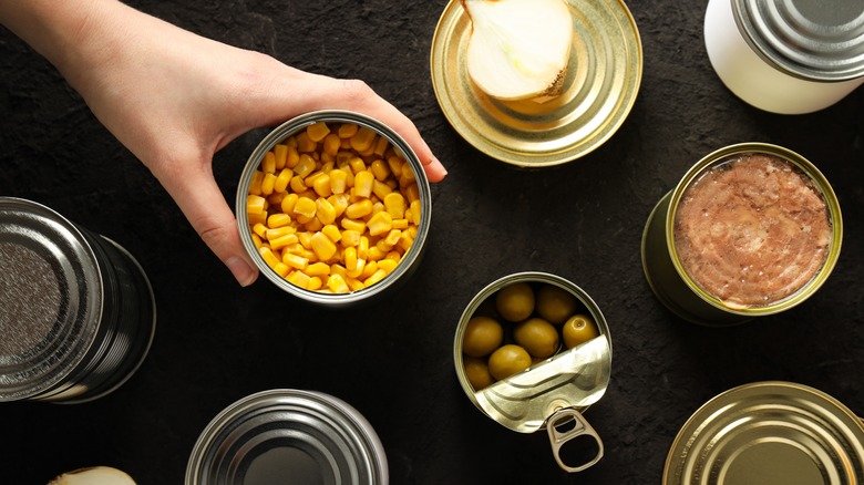 Person reaching for assortment of canned food