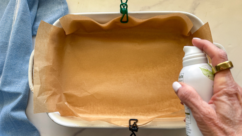 hand spraying dish with cooking spray