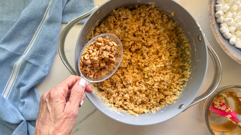 hand adding nuts to pot
