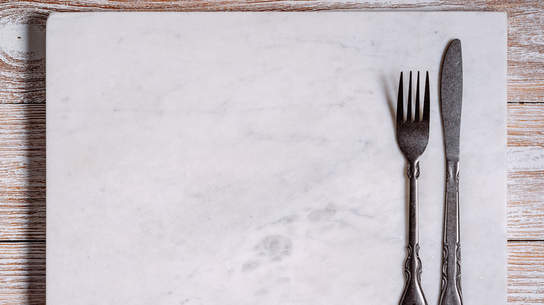 empty marble cutting board with knife and fork