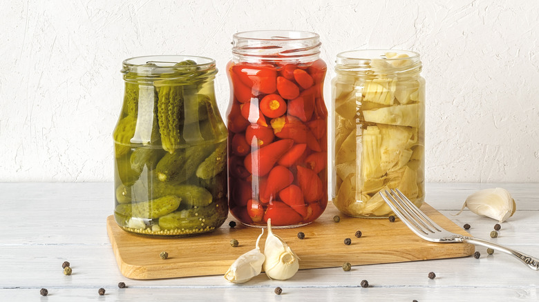 jars of artichoke hearts, hot peppers, and gherkins with garlic cloves and peppercorns