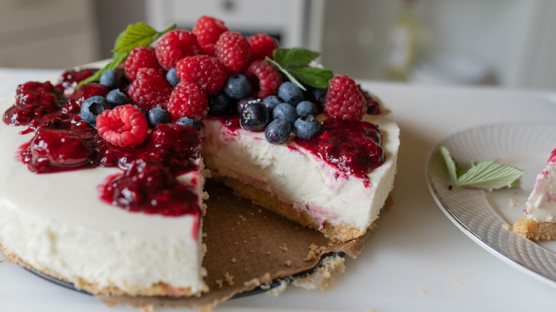 No-bake berry-topped cheesecake with one slice cut out.