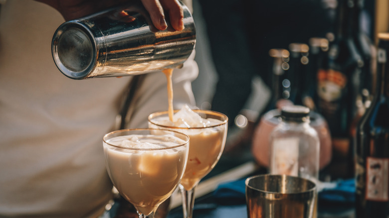 cocktail shaker pouring two drinks with ice