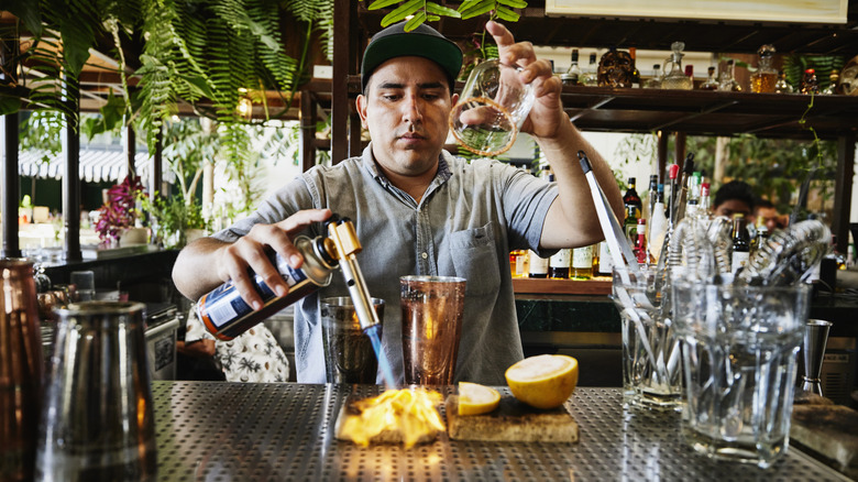 a bartender with a blowtorch and glass