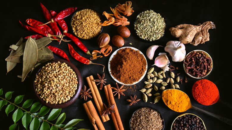 Variety of spices and herbs in ramekins against a dark background
