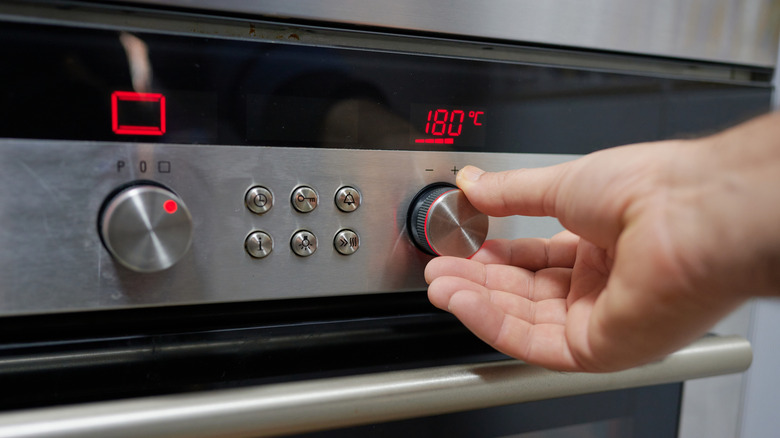 Person setting temperature on oven