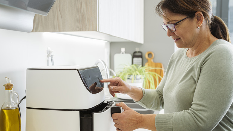 Woman pressing buttons on air fryer