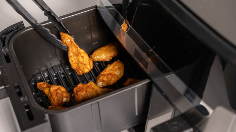 Using tongs to turn chicken in air fryer