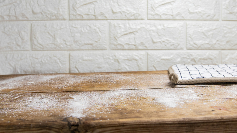 A lightly floured wooden work surface next to a pot holder