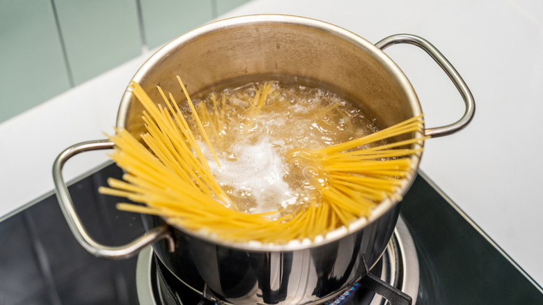 Spaghetti boiling in salted water over a gasoline burner