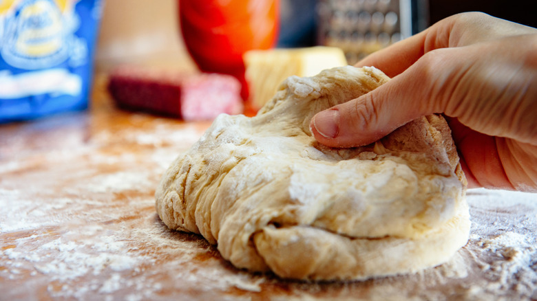 A chef kneading pasta dough on a lightly floured countertop