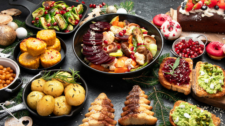 Table of vegan food, including Brussels sprouts, potatoes, avocado toast, and corn on the cob