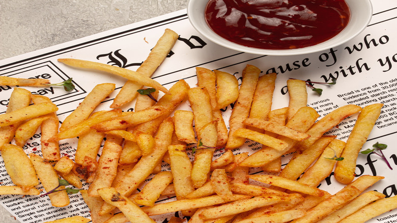 A bowl of gochujang on a table beside French fries
