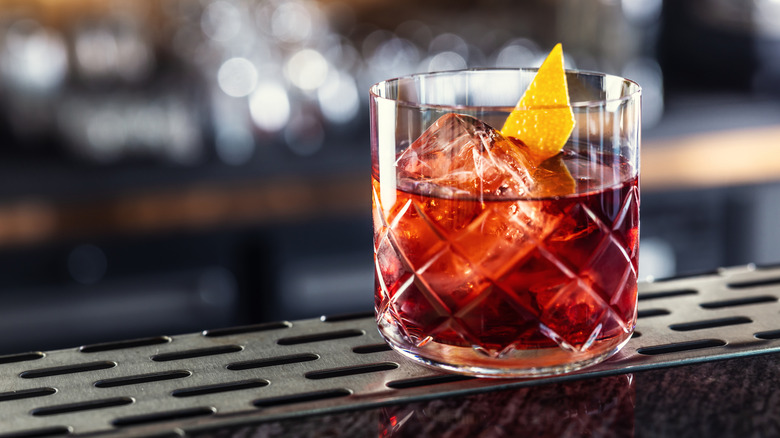 A negroni garnished with lemon sits on a bar counter.