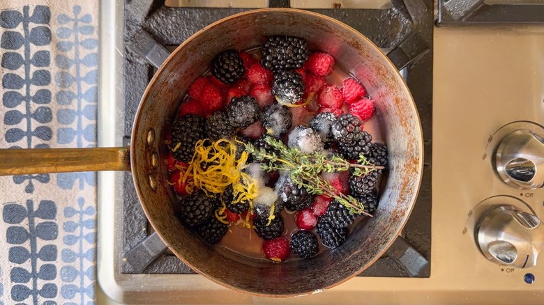 Raspberries, blackberries, lemon zest, sugar, and thyme sprigs in saucepan