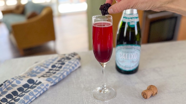 Dropping a frozen blackberry into a mixed berry blood orange mimosa