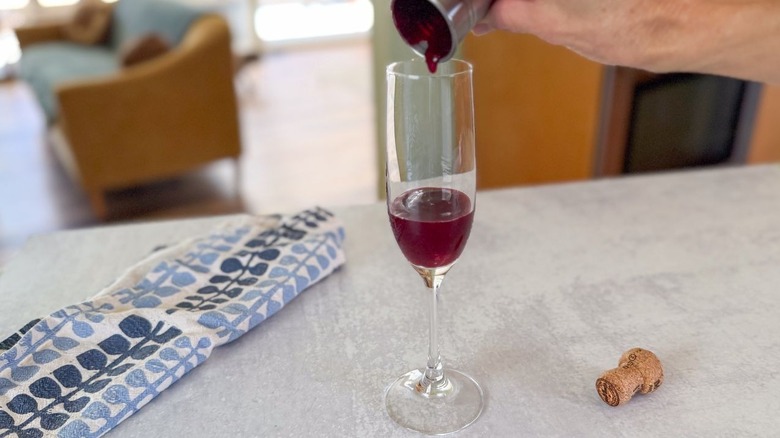 Pouring mixed berry syrup into a champagne flute