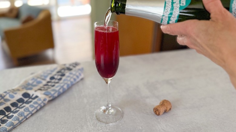 Pouring Cava into a champagne flute with mixed berry blood orange syrup
