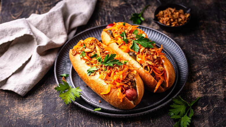 Two hot dogs covered in toppings