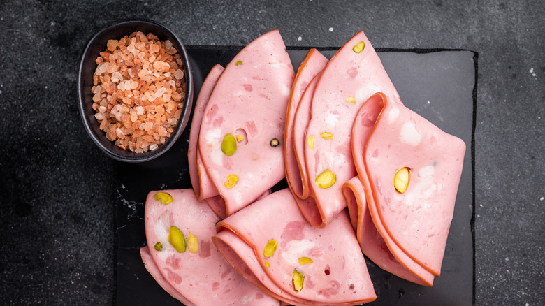 Slices of mortadella folded on a slate plate.