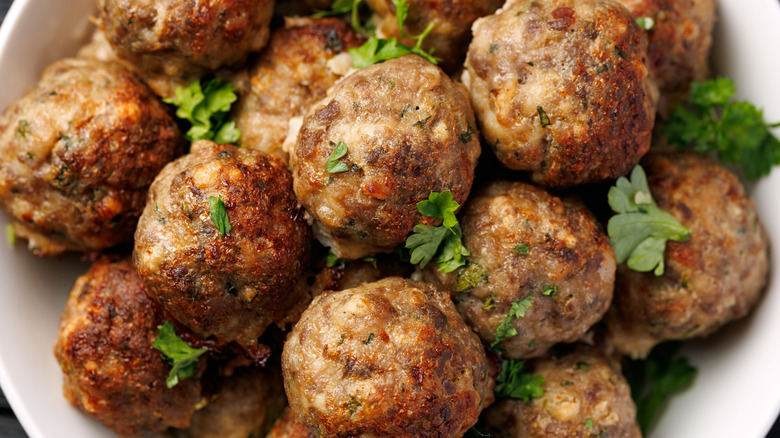Plate full of meatballs garnished with herbs.