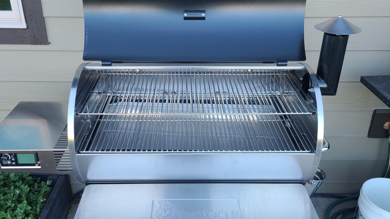 A clean BBQ smoker with an open lid.