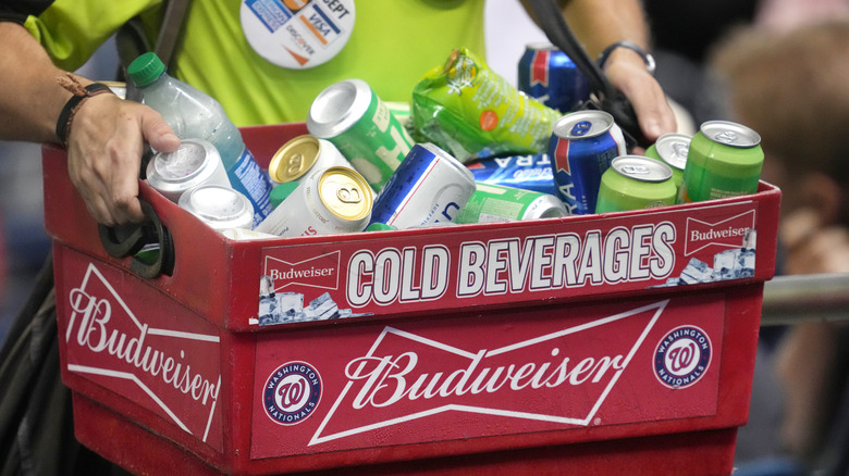 A beer vendor carries a red container filled with beer at a baseball game