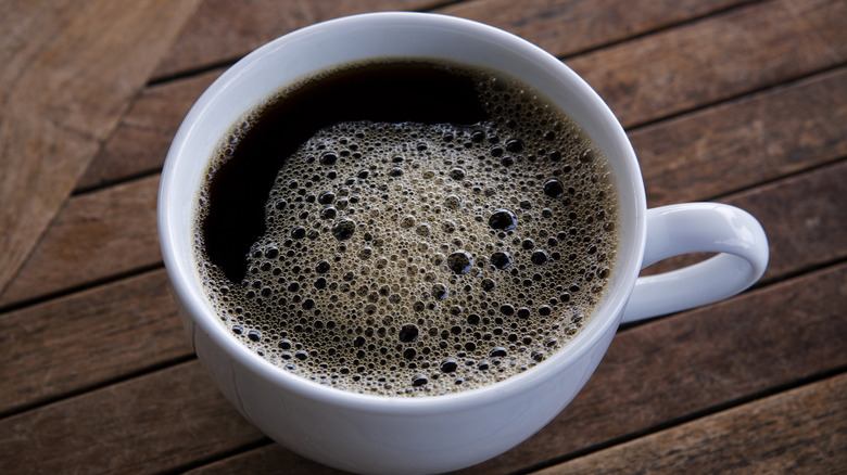 A cup of black Kona coffee on a wooden table.