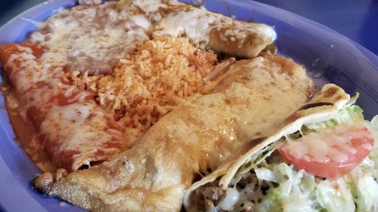 A Mexican combination plate with chile relleno, enchiladas, a taco, refried beans, rice, and salad