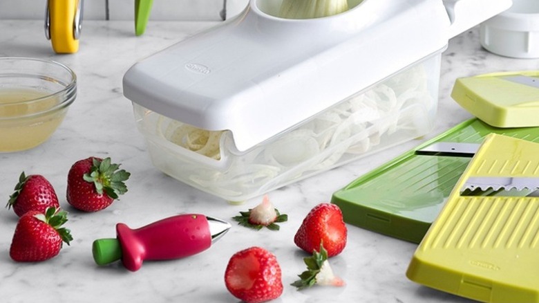 Starwberries and strawberry huller on kitchen counter with other tools.