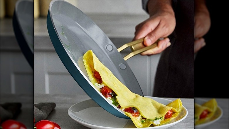 Person holding nonstick pan while omelet slides out onto plate.